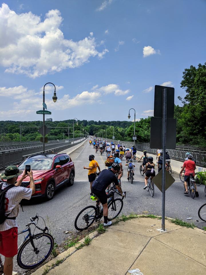 A long line of bicyclists heading across the Strawberry Mansion Bridge, vanishing into the distance.